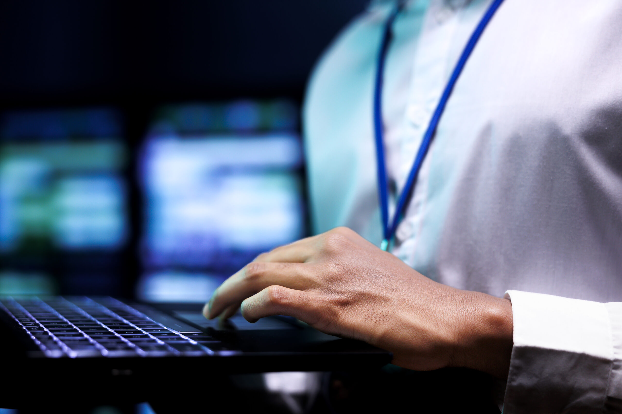 Computer scientist using laptop to analyze server cabinets providing storage. Advanced data center enabling artificial intelligence to process massive datasets for training and complex calculations